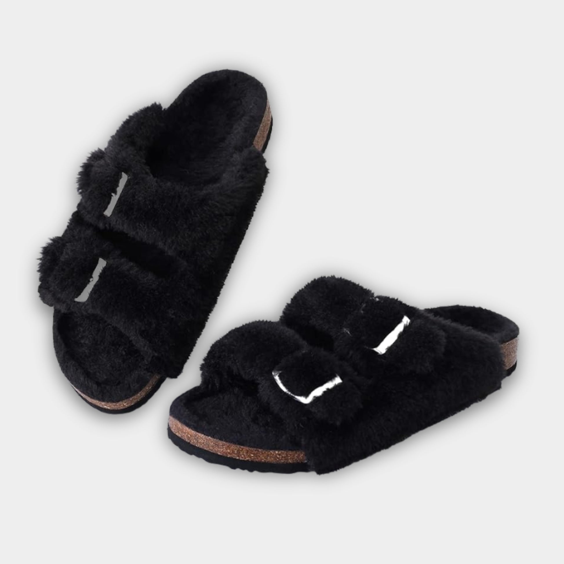 Pair of black fuzzy slippers on a light gray background