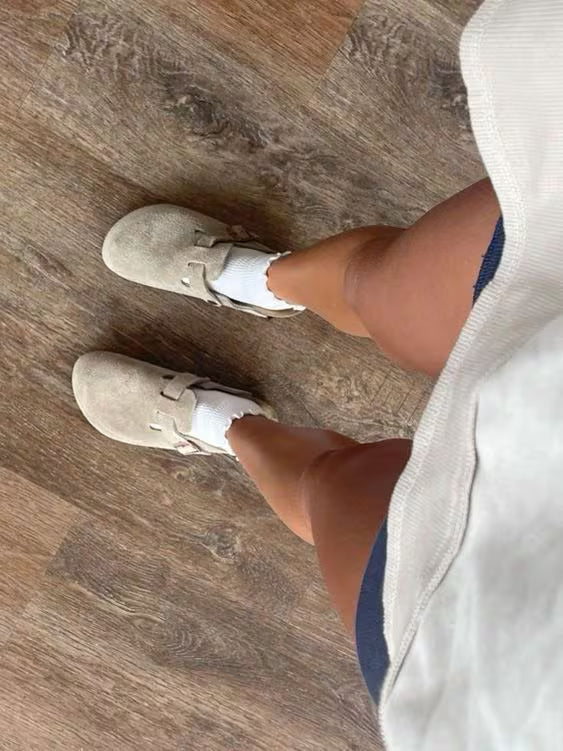 Person wearing beige sneakers on a wooden floor