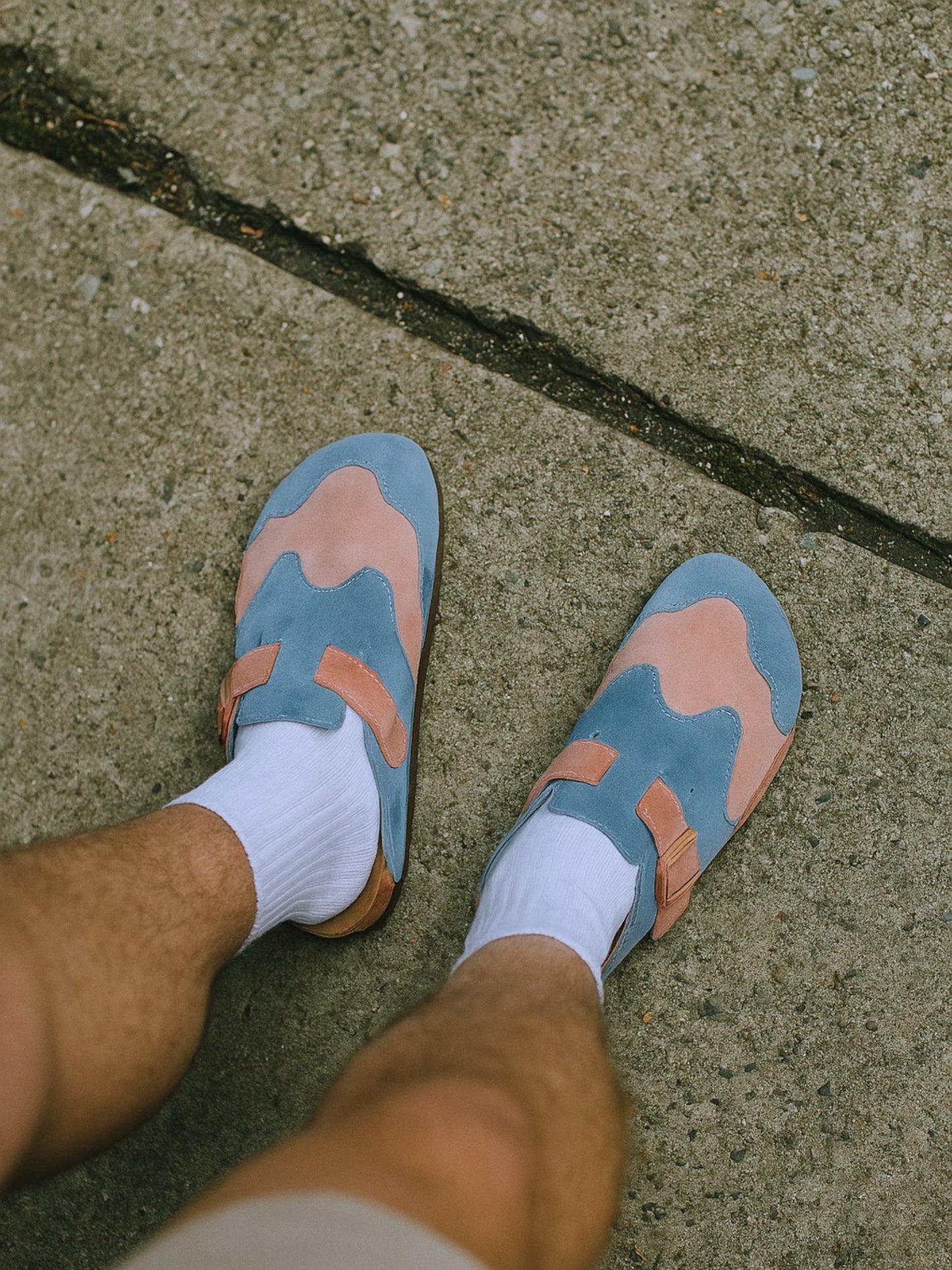 Blue and pink sandals worn on a concrete surface